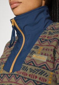 Fleece-pullover med halv-lynlås, marineblå krave og brune detaljer. Har et geometrisk mønster i jordfarver. Columbia-logoet er synligt.