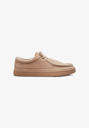 Scarpe casual in pelle beige con punta rotonda, dettagli cuciti e suola piatta in gomma, con un branding minimale sul lato.