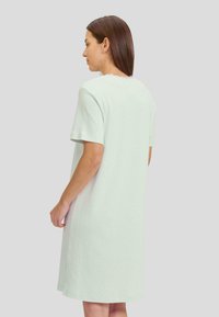 Vestido de manga corta en un verde menta claro con un patrón de zigzag texturizado, que presenta un corte relajado y una silueta recta. Aberturas laterales en el dobladillo.