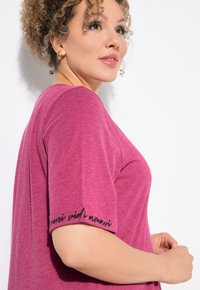 T-shirt met korte mouwen en een ronde hals in gemêleerd bessenstof. Zwarte tekst "veni vidi amavi" op de mouw. Smooth textuur, licht ontspannen pasvorm.