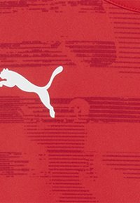 Punane sportlik särk, millel on tekstuuriline muster ja ees suur valge Puma logo. Sile kangas ja ümmargune kaelus.