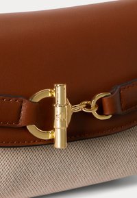 Braune Leder- und beige Stofftasche mit goldfarbenem Knebelverschluss, der mit den Initialen RL graviert ist.
