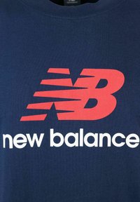 T-shirt in cotone blu navy con un grande logo "new balance" rosso e bianco, arricchito da elementi di design dinamici e colletto rotondo.
