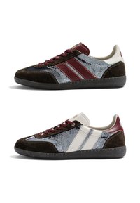 Deux baskets basses en suède marron foncé, avec des panneaux argentés à sequins, des rayures grenat et blanches, des lacets grenat et des semelles noires texturées.