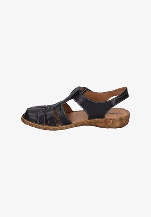 Black leather sandal with cut-out design, adjustable back strap, and textured brown sole. Features white stitching and a rounded toe.
