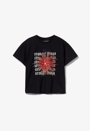 Zwart t-shirt met korte mouwen, met in het midden een rode twaalfzijdige dobbelsteen en gestileerde "Stranger Things"-tekst in een explosieachtig grafisch ontwerp.