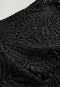 Black lace fabric featuring a wave pattern with intricate cutouts. The texture is lightweight, providing a delicate and airy appearance.