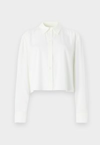 Cropped, long-sleeve shirt in off-white. Features a classic collar, button front, and smooth texture. Simple design without patterns.