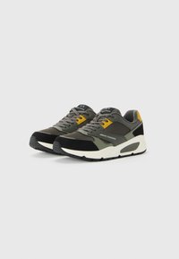 Une paire de baskets Armani Exchange en gris, noir et jaune avec des semelles blanches, des lacets blancs et un détail de marque sur le côté, placées côte à côte.