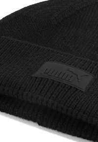 Black knit beanie featuring ribbed texture and a raised, matte black logo patch with "PUMA" lettering on the front.