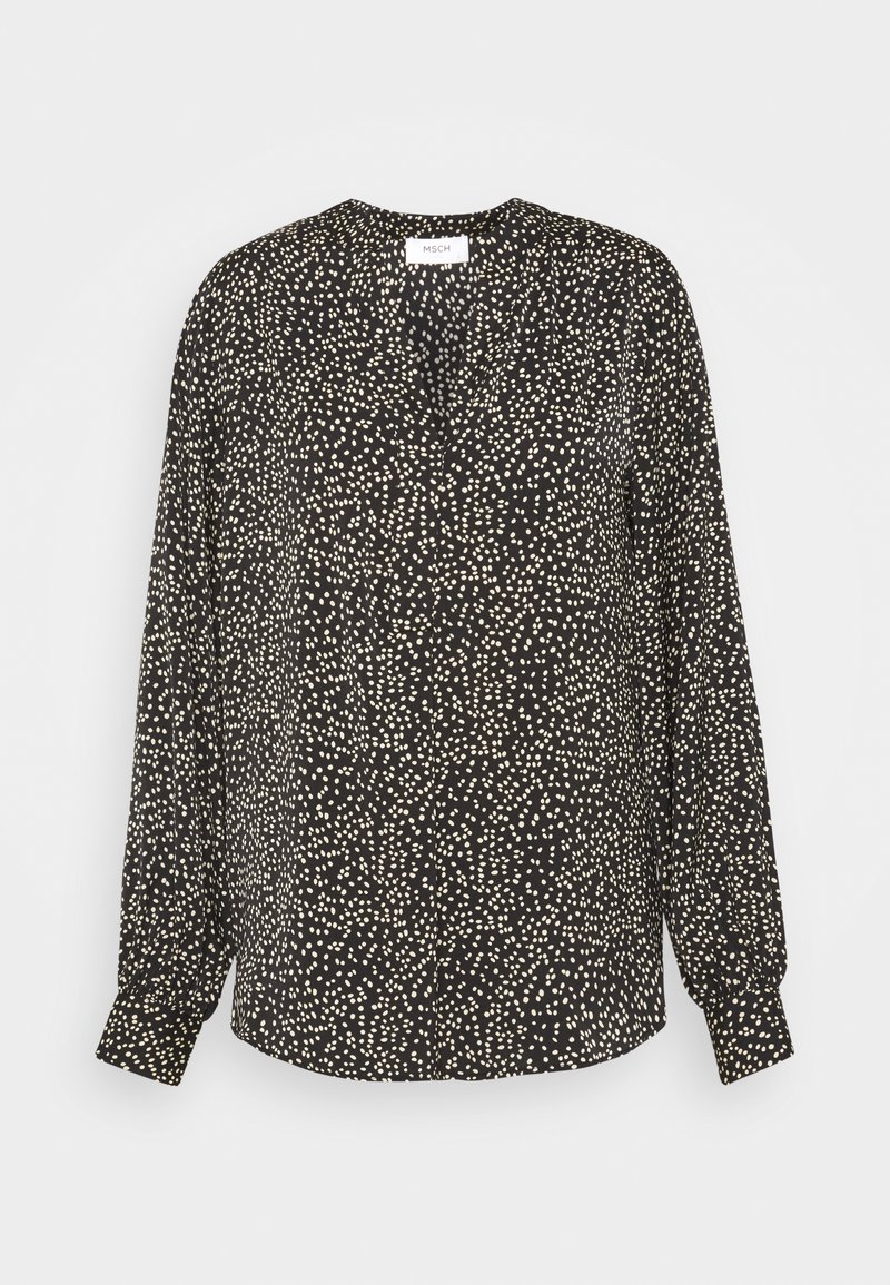 Blouse noire à manches longues avec des pois blancs irréguliers, col rond et poignets boutonnés, présentée sur un fond uni.