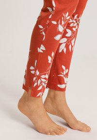 Rode leggings van een katoenmix, met witte bloemmotieven, zijsplitsen aan de zoom, lengte tot de enkels en een zachte textuur.