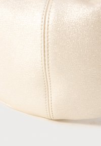 Pochette di colore crema con texture e una leggera lucentezza, caratterizzata da una cerniera liscia e dettagli di cucitura a contrasto. Forma arrotondata.