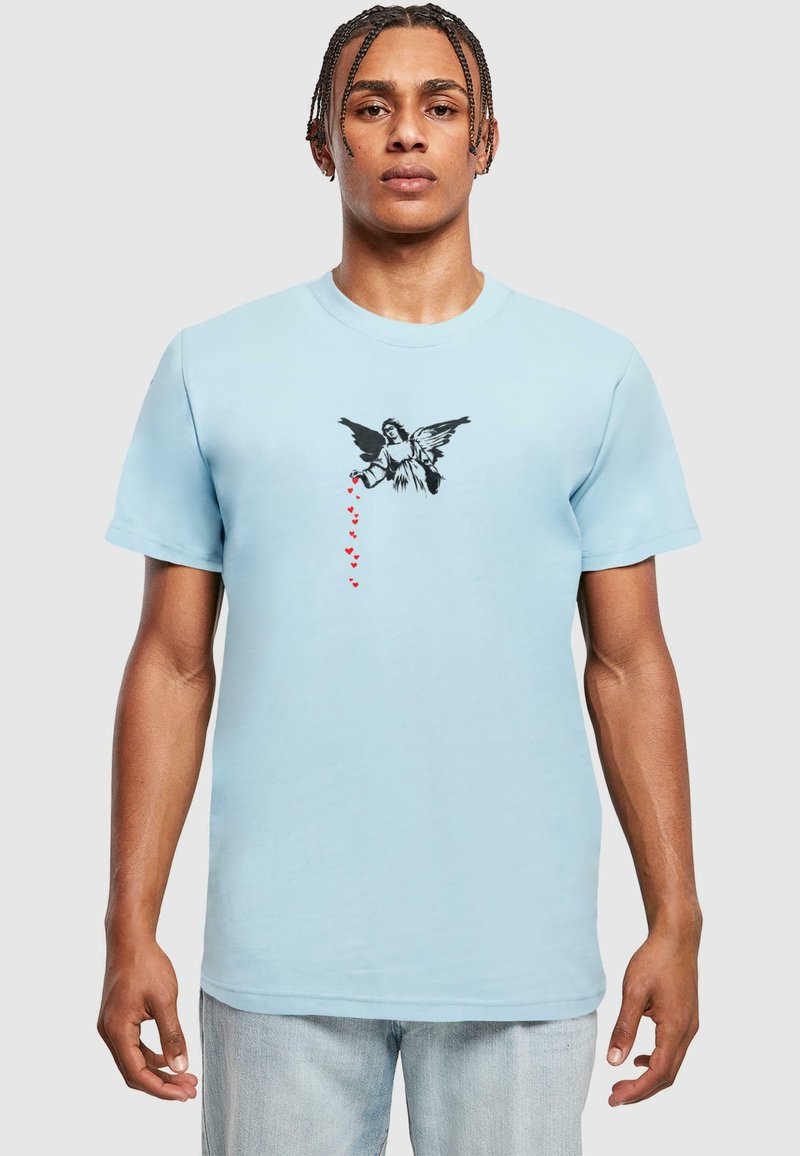 T-shirt en coton bleu clair avec un graphique central d'ange noir et des cœurs rouges qui descendent, à manches courtes et col rond.