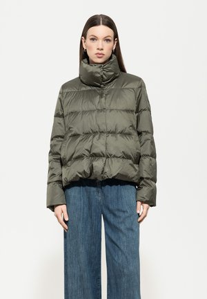 Olivgrüne Daunenjacke mit hohem Kragen, gestepptem Textur und Knopfverschluss. Getragen über weit geschnittenen Jeanshosen.
