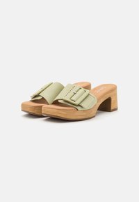 Gröna tygslip-on skor med ett brett band som har en rektangulär spänne. Rund tå, träklack och texturerad sula.