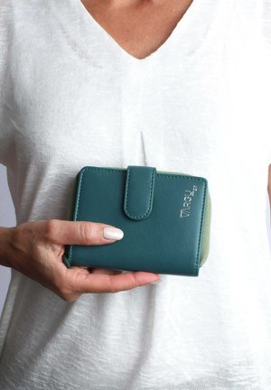 Portefeuille en cuir teal avec fermeture à pression, coins arrondis et doublure intérieure verte contrastante. Présente une marque en relief sur le devant.