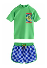 Maglietta a maniche corte verde con grafica di limone, abbinata a costumi da bagno a quadri blu e bianchi con una vita verde e un cordoncino giallo.