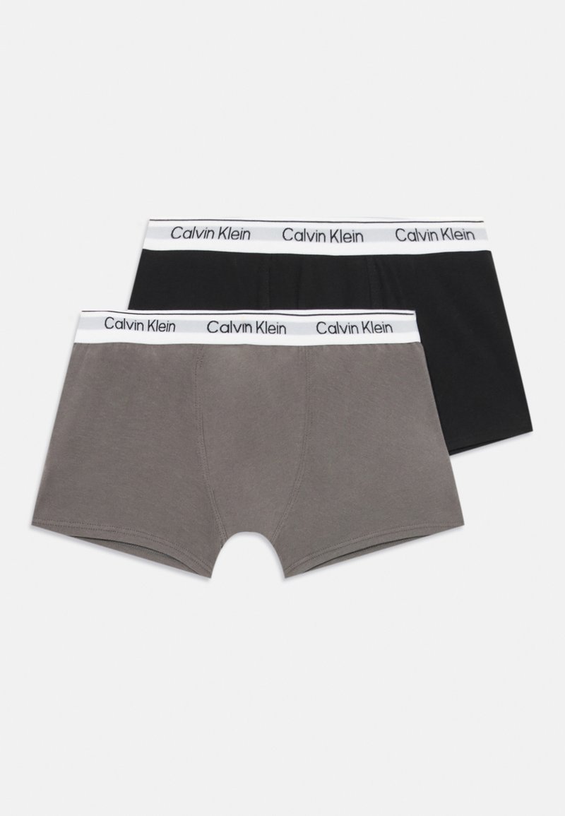 Divi vīriešu bokseršorti, viens melns un otrs pelēks, katram ir balta josta ar atkārtotiem Calvin Klein zīmoliem.