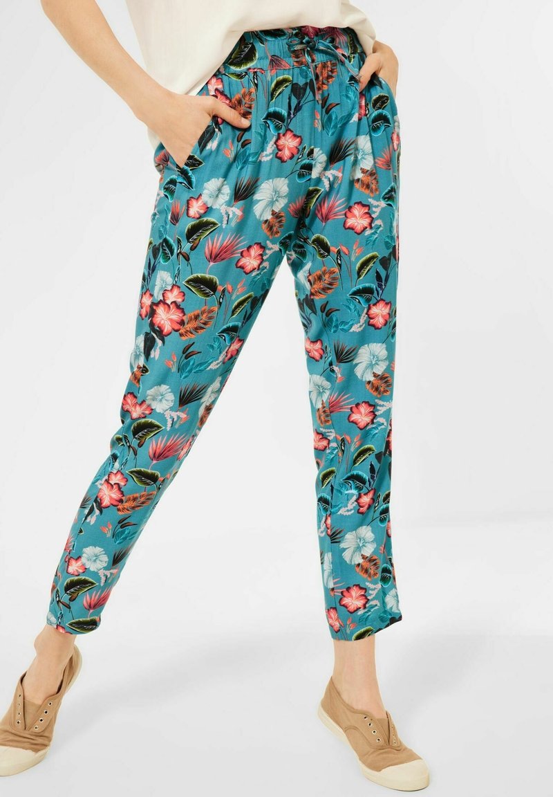 Blumenmuster-Hosen in Türkis mit elastischem Bund, Seitentaschen und einer lockeren Passform. Das Material hat eine glatte Textur.