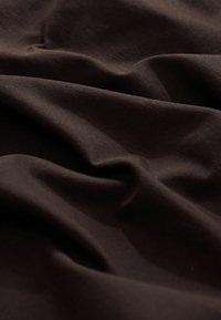Donkerbruine stof met zachte plooien en een gladde, licht geribbelde textuur, met zachte schaduwen en hooglichten.