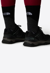 Black hiking shoes with gray accents, textured upper, and durable soles. Paired with black and gray The North Face socks.