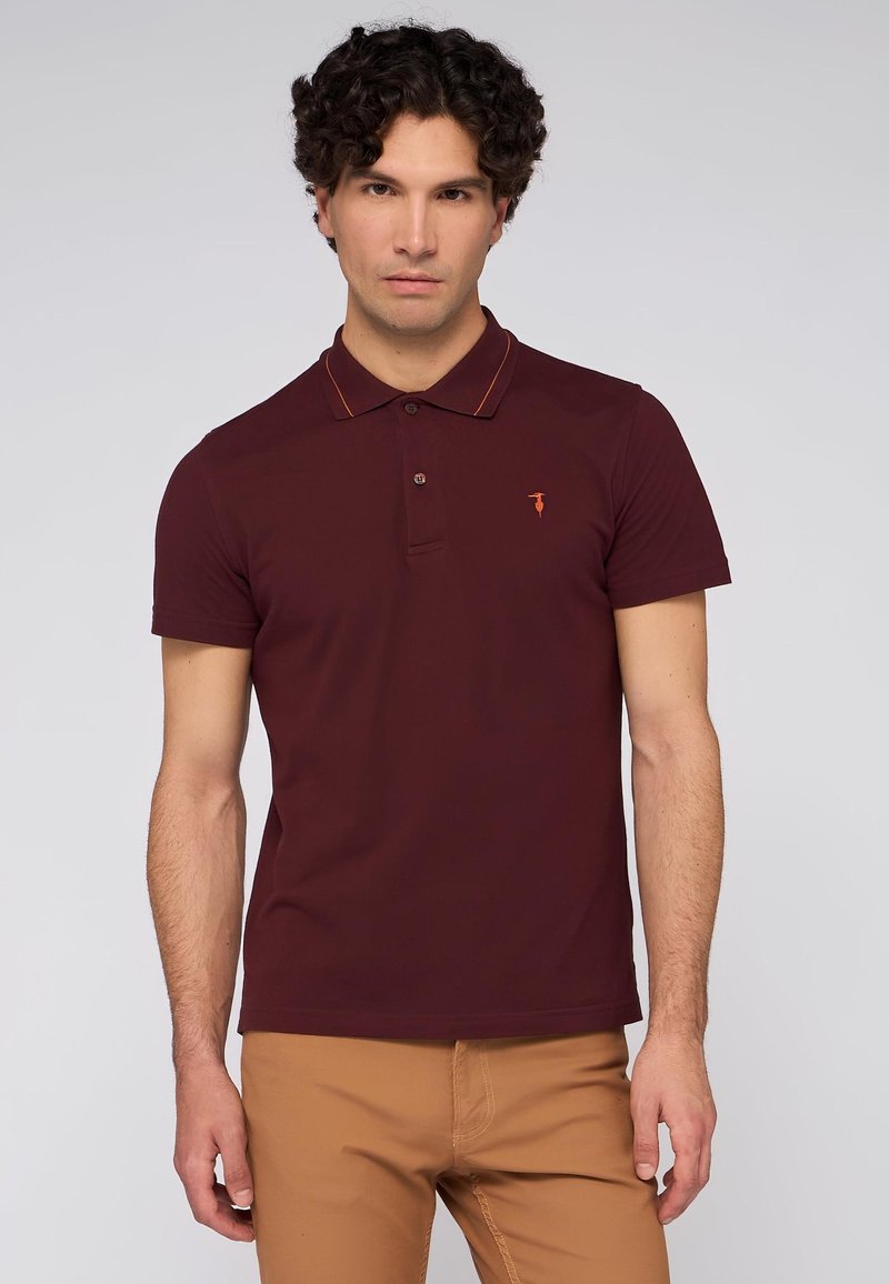 Bordová polo košile s dvoupolohovým knoflíkem, oranžovým lemem límce a malým logem na levé hrudi. Měkký bavlněný materiál, krátké rukávy.