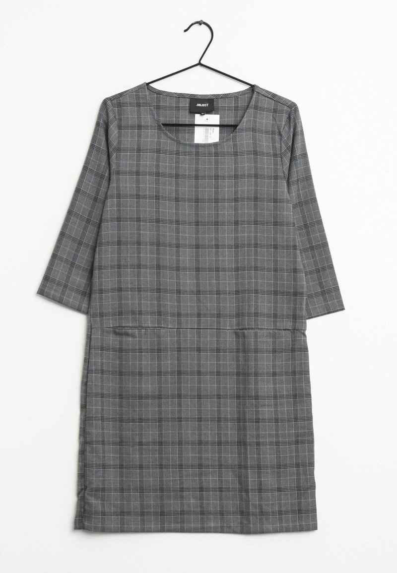 Robe grise à carreaux avec un col rond et des manches trois quarts. Elle présente des lignes verticales et horizontales, ainsi que deux poches avant.