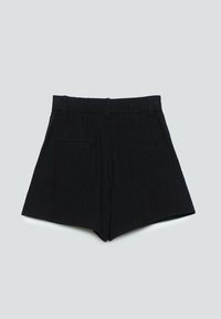 Shorts noirs taille haute avec passants pour ceinture, deux poches arrière, et une coupe ajustée avec une ouverture de jambe légèrement évasée sur un fond gris clair.