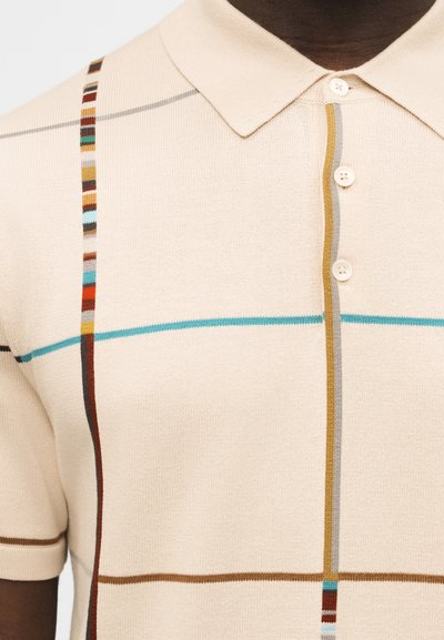 Polo beige à manches courtes avec des rayures verticales et horizontales multicolores, trois boutons à l'avant, et un col classique.