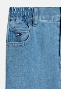 Tessuto di jeans blu chiaro caratterizzato da una piccola tasca con un accento di logo in rosso, bianco e blu. Vita elastica per il massimo comfort.