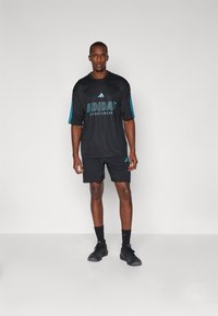 Black Adidas sportswear outfit including a short-sleeve jersey with blue accents and shorts, featuring logo and mesh texture.