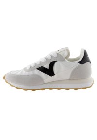 Zapatilla blanca con acentos de ante gris, logo negro y lengua texturizada. Presenta una suela de goma voluminosa con un patrón amarillo. Diseño clásico con cordones.