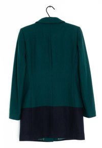 Manteau vert foncé avec un col structuré, des manches longues et une partie inférieure bleu marine. Confectionné en laine, il présente une texture lisse et un design minimaliste.