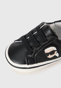 Czarne trampki dla malucha z trzema czarnymi elastycznymi paskami, białą podeszwą oraz rysunkiem na boku przedstawiającym twarz ośmiorniczki w okularach przeciwsłonecznych.