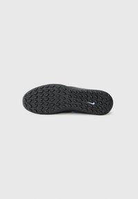 Black athletic shoe sole with a textured rubber surface featuring an intricate hexagonal pattern; includes a small blue accent detail.