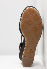 Czarne espadryle na płaskiej podeszwie z teksturowanej gumy, z plecionym akcentem z juty. Podeszwa ma wzór diamentowy i centralne logo.