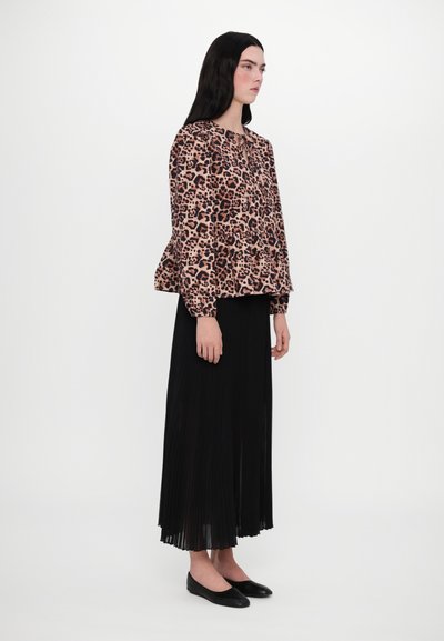 Leopard print top with long sleeves and peplum hem paired with a pleated black maxi skirt and black flat shoes. Simple, contemporary design.