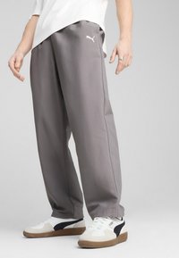 Pantalones grises, holgados y de un material ligero, con una cintura elástica y un pequeño logotipo en el muslo izquierdo.