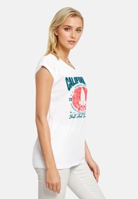 White short-sleeve t-shirt featuring a colorful graphic design with text and palm trees, made from soft cotton material.