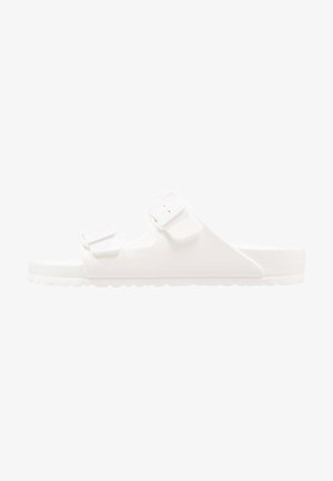 Sandales blanches avec deux sangles réglables. Fabriquées en plastique souple, elles possèdent une semelle intérieure texturée et une semelle extérieure robuste et crantée pour une meilleure adhérence.