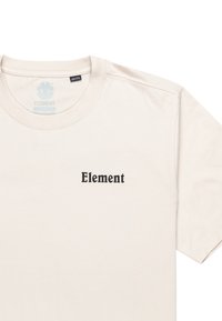 Camiseta de manga corta de color beige claro, fabricada en algodón, con el texto "Element" en negro en un tipo de letra en negrita en el pecho. Cuello redondo.
