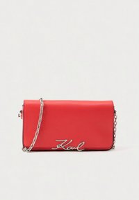 Rote Ledertasche mit schlanker, rechteckiger Form, silberner Kettenriemen und hervorgehobenem "Karl"-Logo in Schreibschrift auf der Vorderseite.