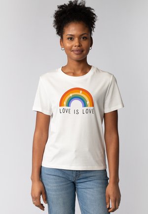 T-shirt blanc à manches courtes arborant un graphique coloré d'arc-en-ciel et le texte "L'AMOUR EST AMOUR" en dessous de l'arc. Matériau en coton doux.
