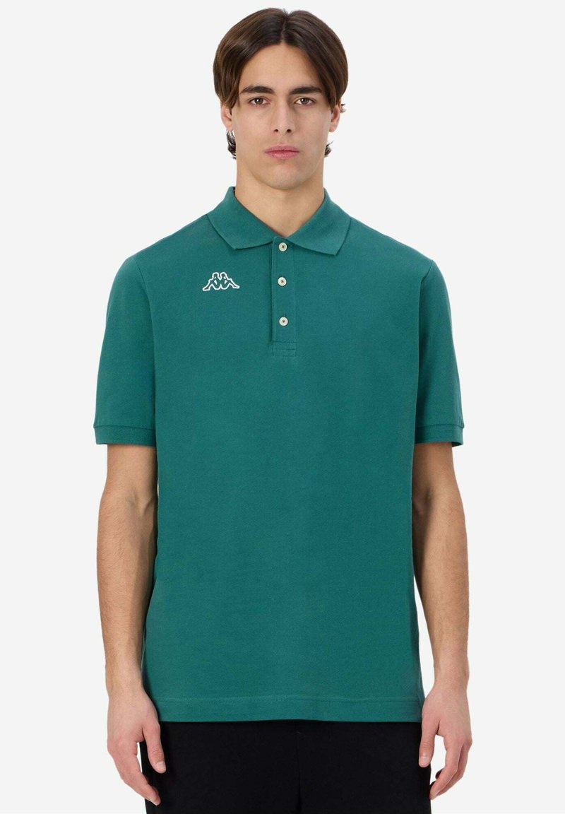 Polo shirt verde a maniche corte in cotone, con colletto bottonato e logo bianco sul lato sinistro del petto. Texture liscia.