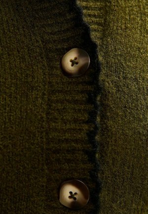 Olijfgroen gebreide cardigan met een gestructureerde stof en twee ronde, lichte knopen met vier gaten.