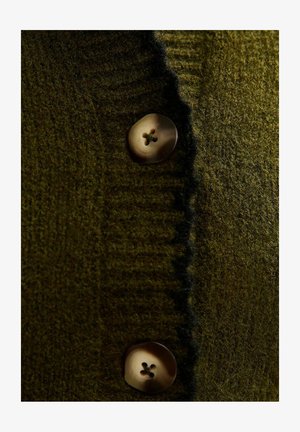 Olivgrüner Strickcardigan mit strukturiertem Stoff und zwei runden, hellen Knöpfen mit vier Löchern.