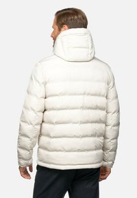 Vit puffjacka med hög krage och en figurnära design, med horisontella quiltade sektioner och en bakhuva för extra värme.