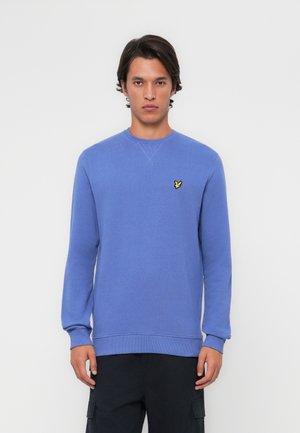 Sweatshirt bleu clair à col rond fabriqué en tissu doux, arborant un petit logo de papillon jaune sur la poitrine, avec des poignets et un ourlet côtelés.