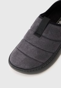 Szürke párnázott slip-on cipő fekete rugalmas húzófüllel és fekete gumitalppal, a kényelem és a könnyű viselhetőség érdekében tervezve.